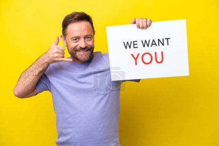 Photo for Middle age caucasian man isolated on yellow background holding We Want You board and making phone gesture - Royalty Free Image
