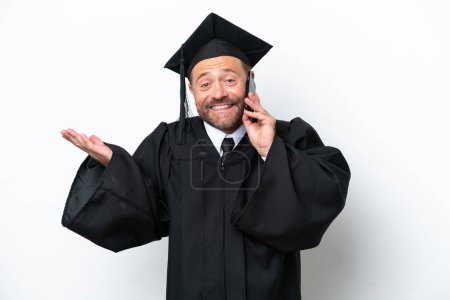 Foto de Graduado universitario de mediana edad aislado sobre fondo blanco manteniendo una conversación con el teléfono móvil con alguien - Imagen libre de derechos