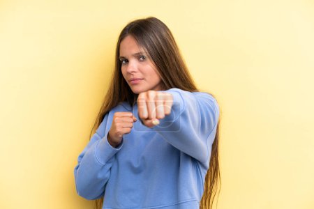 Photo for Young caucasian woman isolated on yellow background with fighting gesture - Royalty Free Image