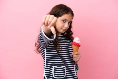 Photo for Little caucasian girl holding an ice cream isolated on pink background showing thumb down with negative expression - Royalty Free Image