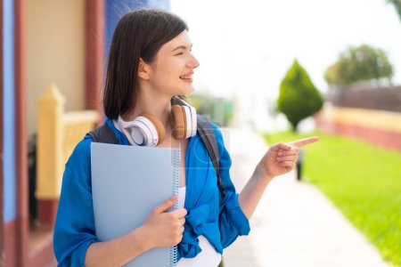 Photo for Young pretty Ukrainian student woman at outdoors pointing to the side to present a product - Royalty Free Image