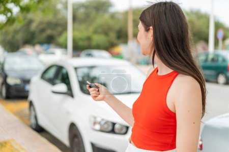 Téléchargez les photos : Jeune jolie femme à l'extérieur tenant des clés de voiture - en image libre de droit