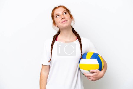 Téléchargez les photos : Jeune femme caucasienne rougeâtre jouant au volley isolé sur fond blanc et levant les yeux - en image libre de droit
