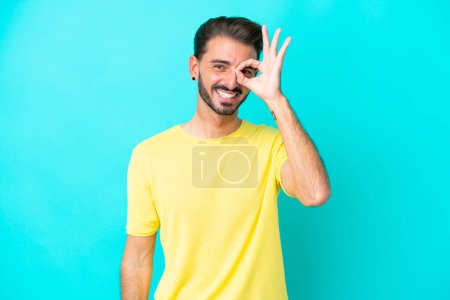 Photo for Young caucasian man isolated on blue background showing ok sign with fingers - Royalty Free Image