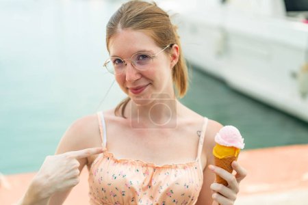 Foto de Chica francesa con gafas sosteniendo un helado de corneta al aire libre con expresión facial sorpresa - Imagen libre de derechos