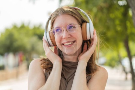 Téléchargez les photos : Jeune fille française avec des lunettes à l'extérieur écouter de la musique - en image libre de droit