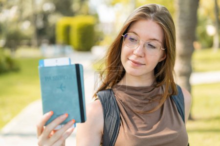 Téléchargez les photos : Jeune fille française avec des lunettes à l'extérieur tenant un passeport et avec une expression triste - en image libre de droit