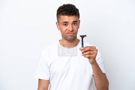 Photo for Young Brazilian man shaving his beard isolated on white background with sad expression - Royalty Free Image