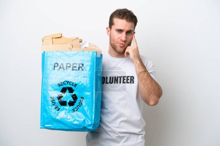 Téléchargez les photos : Jeune homme caucasien tenant un sac de recyclage plein de papier pour recycler isolé sur fond blanc penser une idée - en image libre de droit