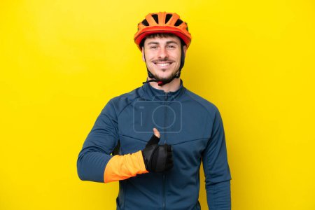 Téléchargez les photos : Jeune cycliste caucasien isolé sur fond jaune donnant un pouce geste - en image libre de droit