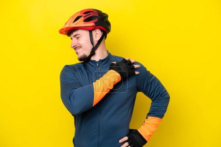 Téléchargez les photos : Jeune cycliste caucasien isolé sur fond jaune souffrant de douleur à l'épaule pour avoir fait un effort - en image libre de droit