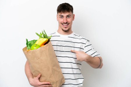 Photo for Young caucasian man holding a grocery shopping bag isolated on white background with surprise facial expression - Royalty Free Image
