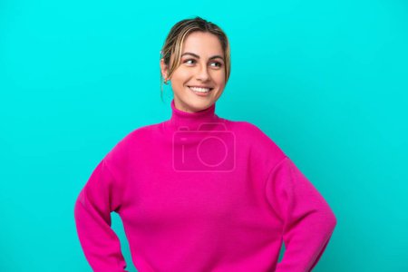Photo for Young caucasian woman isolated on blue background posing with arms at hip and smiling - Royalty Free Image