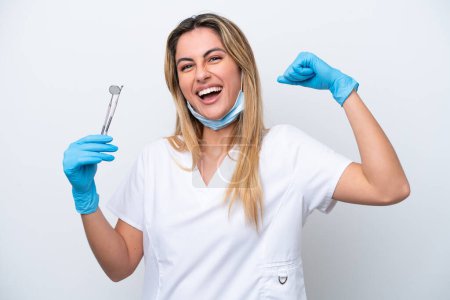 Téléchargez les photos : Dentiste femme tenant des outils isolés sur fond blanc faisant un geste fort - en image libre de droit