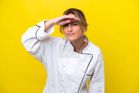 Photo for Uruguayan chef woman isolated on yellow background looking far away with hand to look something - Royalty Free Image