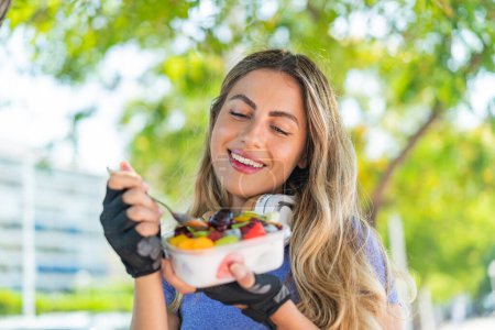 Photo for Young blonde woman holding a bowl of fruit at outdoors - Royalty Free Image