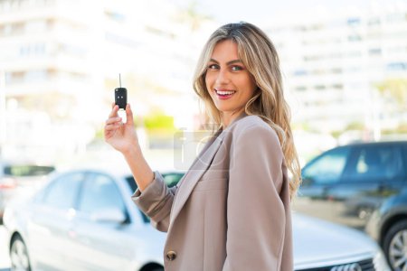 Téléchargez les photos : Jolie femme uruguayenne blonde tenant des clés de voiture à l'extérieur souriant beaucoup - en image libre de droit