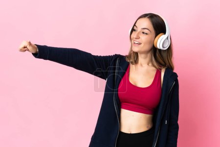 Foto de Joven mujer deportiva rumana aislada sobre fondo rosa dando un gesto pulgar hacia arriba - Imagen libre de derechos