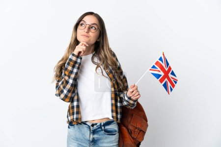 Young Romanian woman holding an United Kingdom flag isolated on white background and looking up
