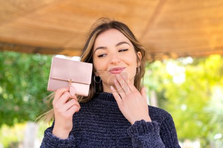 Photo for Young pretty Romanian woman holding a wallet at outdoors - Royalty Free Image