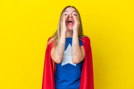 Super Hero Romanian woman isolated on yellow background shouting and announcing something