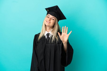 Foto de Joven graduado universitario sobre fondo azul aislado contando cinco con los dedos - Imagen libre de derechos
