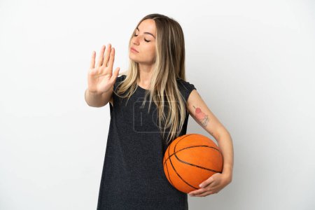 Foto de Mujer joven jugando baloncesto sobre la pared blanca aislada haciendo gesto de parada y decepcionado - Imagen libre de derechos