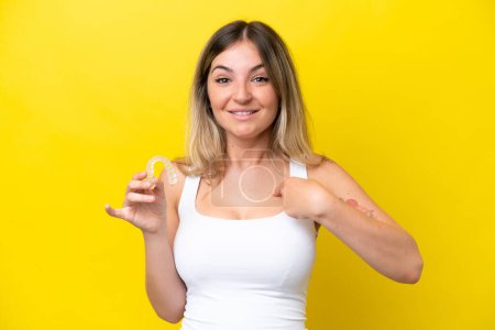 Photo for Young Rumanian woman holding envisaging isolated on yellow background with surprise facial expression - Royalty Free Image