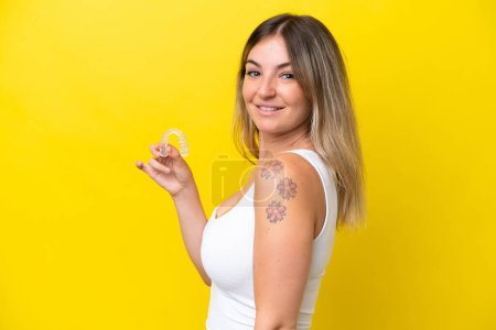 Téléchargez les photos : Jeune femme roumaine qui envisage isolé sur fond jaune souriant beaucoup - en image libre de droit