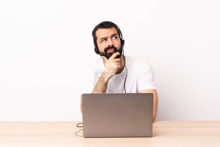 Photo for Telemarketer caucasian man working with a headset and with laptop having doubts. - Royalty Free Image