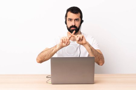 Téléchargez les photos : Télévendeur caucasien homme travaillant avec un casque et avec ordinateur portable faisant geste d'arrêt avec sa main pour arrêter un acte
. - en image libre de droit