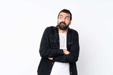 Young man with beard over isolated white background making doubts gesture while lifting the shoulders