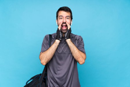 Photo for Young sport man with beard over isolated blue background shouting and announcing something - Royalty Free Image