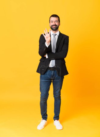 Téléchargez les photos : Plan complet de l'homme d'affaires sur fond jaune isolé heureux et comptant quatre avec les doigts - en image libre de droit
