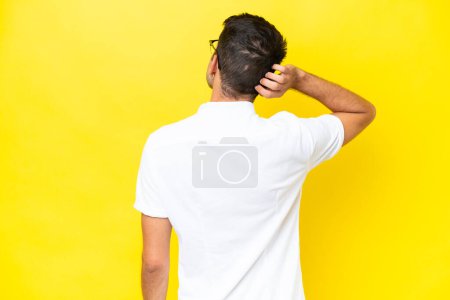 Photo for Young handsome man over isolated yellow background in back position and thinking - Royalty Free Image