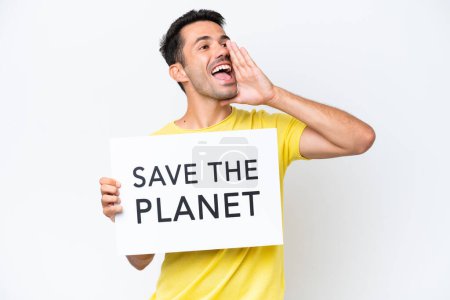Foto de Joven hombre guapo sobre fondo blanco aislado sosteniendo un cartel con texto Save the Planet y gritando - Imagen libre de derechos