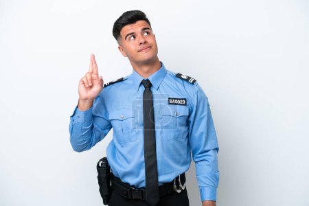 Photo for Young police caucasian man isolated on white background with fingers crossing and wishing the best - Royalty Free Image