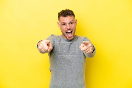 Photo for Young caucasian handsome man isolated on yellow background surprised and pointing front - Royalty Free Image