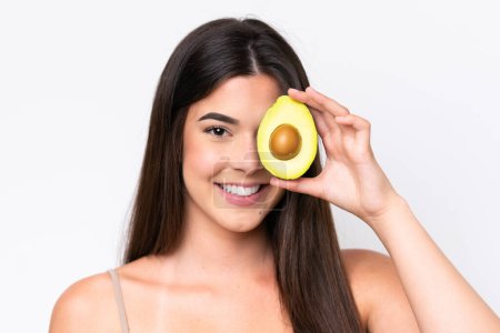 Photo for Young Brazilian woman isolated on white background holding an avocado while smiling. Close up portrait - Royalty Free Image