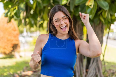 Téléchargez les photos : Jeune jolie Brésilienne avec des lunettes à l'extérieur célébrant une victoire - en image libre de droit