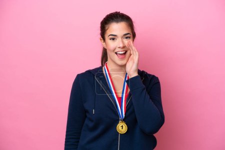 Photo for Young Brazilian sport woman with medals isolated on pink background shouting with mouth wide open - Royalty Free Image