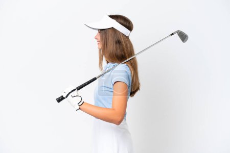 Foto de Mujer joven caucásica aislada sobre fondo blanco jugando al golf en posición lateral - Imagen libre de derechos