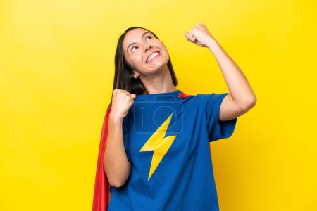 Photo for Young caucasian woman isolated on yellow background in superhero costume and celebrating a victory - Royalty Free Image