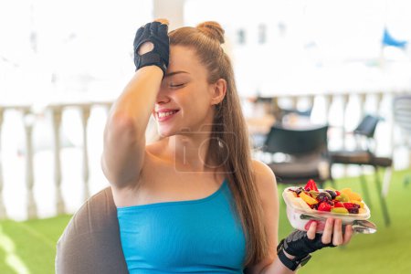 Téléchargez les photos : Jeune jolie fille sportive tenant un bol de fruits à l'extérieur a réalisé quelque chose et l'intention de la solution - en image libre de droit