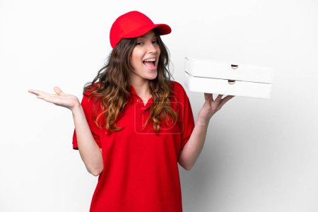 Téléchargez les photos : Pizza delivery woman with work uniform picking up pizza boxes isolated on white background with shocked facial expression - en image libre de droit