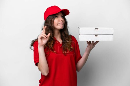 Photo for Pizza delivery woman with work uniform picking up pizza boxes isolated on white background with fingers crossing and wishing the best - Royalty Free Image