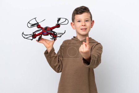 Little Caucasian boy holding a drone isolated on white background doing coming gesture