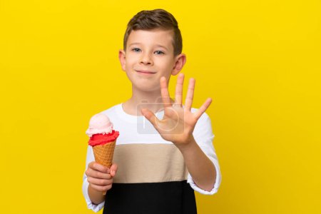 Photo for Little caucasian boy with a cornet ice cream isolated on yellow background counting five with fingers - Royalty Free Image
