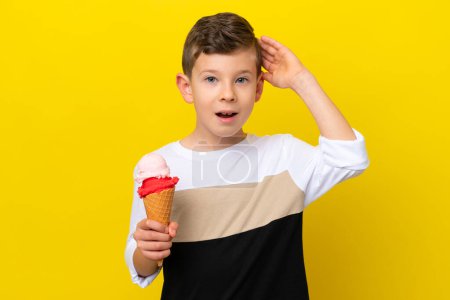 Téléchargez les photos : Petit garçon caucasien avec une crème glacée cornet isolé sur fond jaune avec expression surprise - en image libre de droit