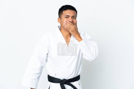 Foto de Joven ecuatoriano haciendo karate aislado sobre fondo blanco alegre y sonriente cubriendo boca con mano - Imagen libre de derechos